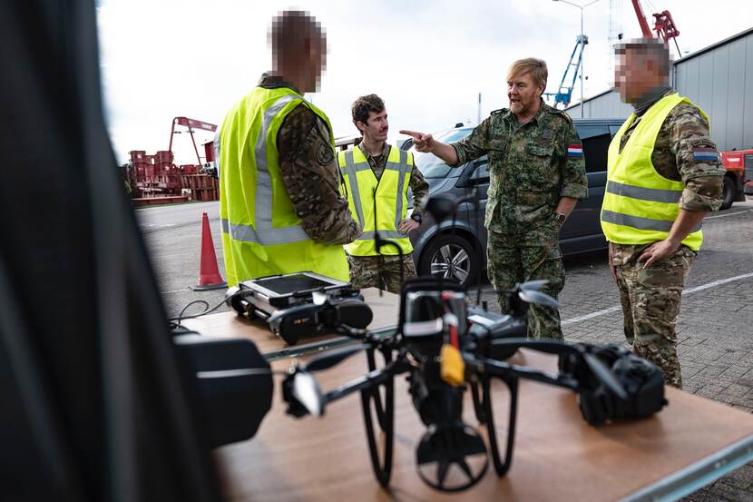 De koning in gesprek met een drone op de voorgrond.