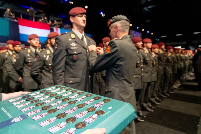 Op de voorgrond medailles, daarachter militairen.