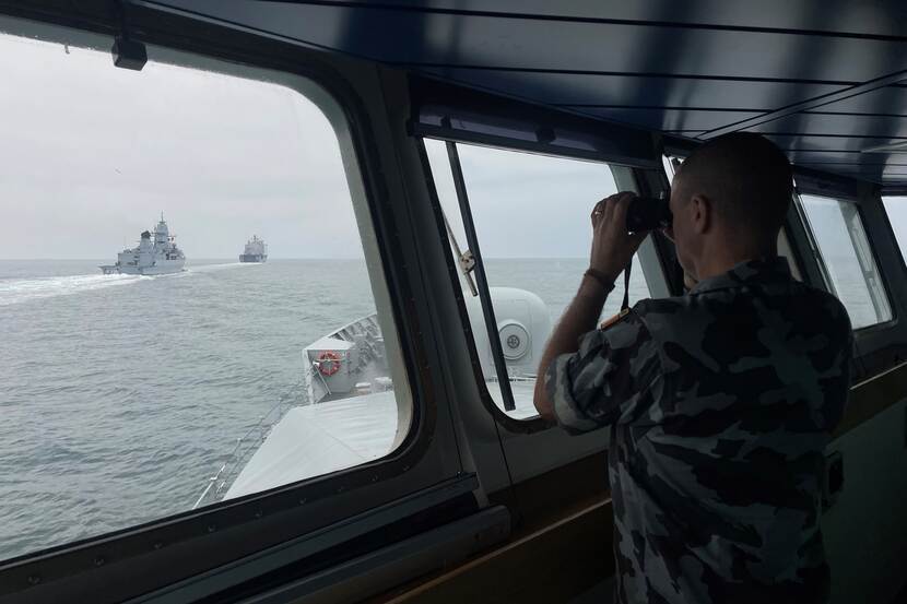 Een opvarende van het Ierse marineschip LÉ William Butler Yeats bekijkt met en verrekijker de navigatieoefening.