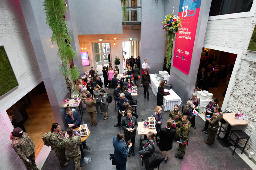 Vrouwelijke deelnemers, veelal in uniform van bovenaf gezien. Ze hebben koffie en thee in hun hand.