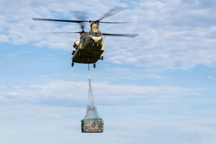 Chinookhelikopter heeft spullen onder het toestel hangen.