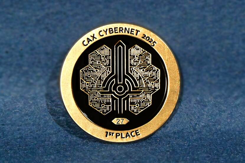 Goudkleurige coin van CAX Cybernet 2025 met tekst '1st place' erop.