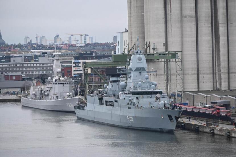 Twee marineschepen aan de kade. Industrie op achtergrond.