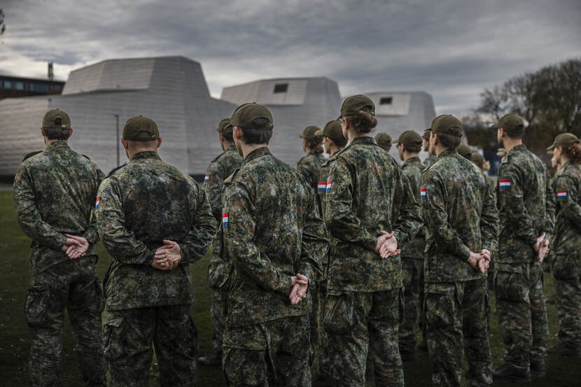 Een 15-tal reservisten in uniform met een petje op en de handen op de rug.
