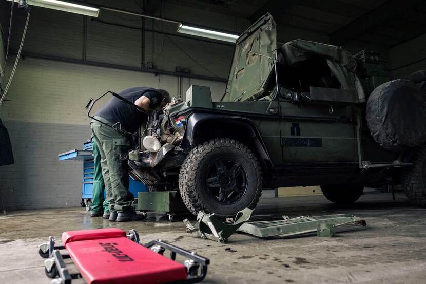 Militair sleutelt aan voertuig.