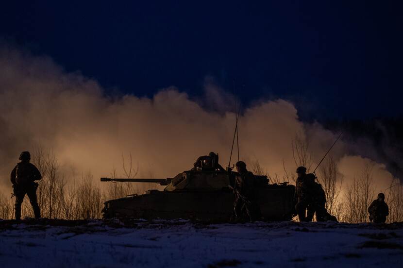 Militairen in de sneeuw en bij duisternis bij gevechtsvoertuig CV90.