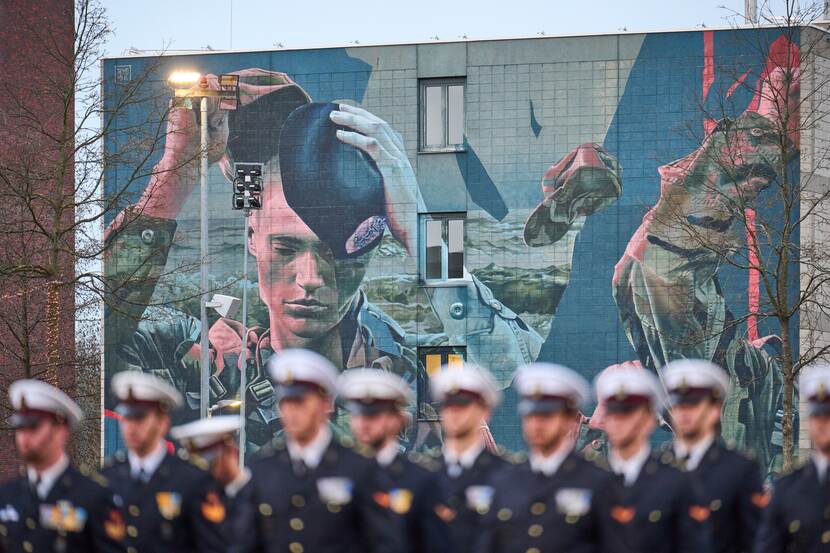 Militairen op een rij voor grote muurschildering.