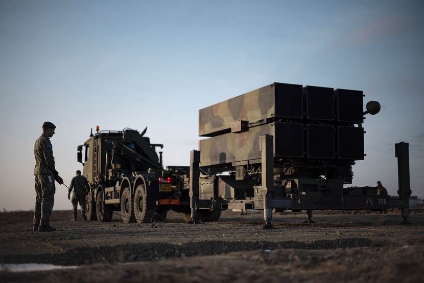 2 militairen staan bij een luchtafweersysteem.