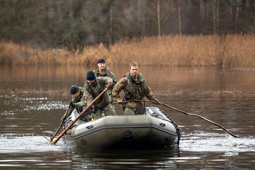 4 militairen in rubberboot op het water.