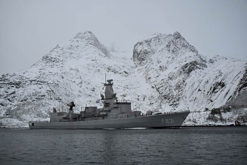 Het schip de Zr.Ms. Van Amstel vaart voor besneeuwde rotsen langs.