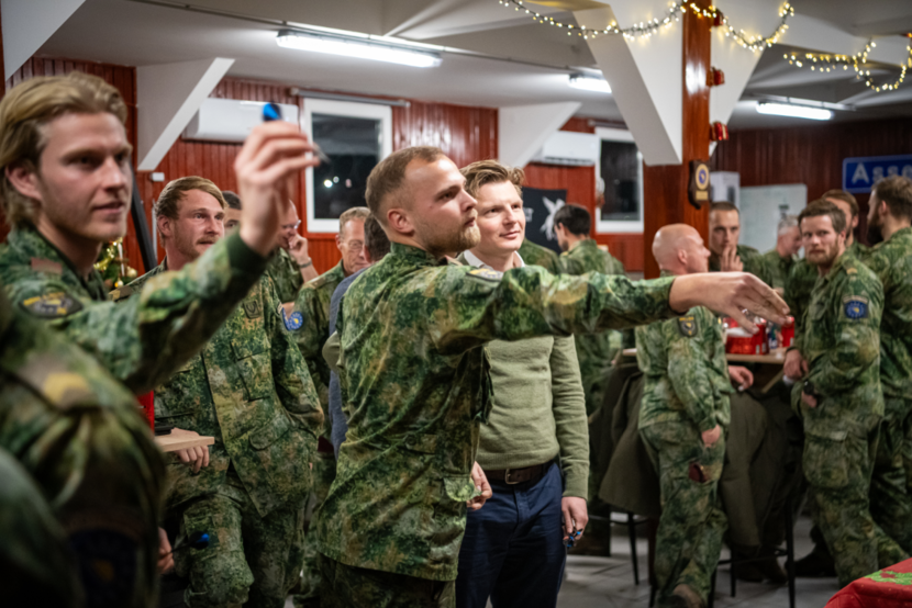 Brekelmans en een aantal militairen in uniform. 2 gooien net pijltjes.