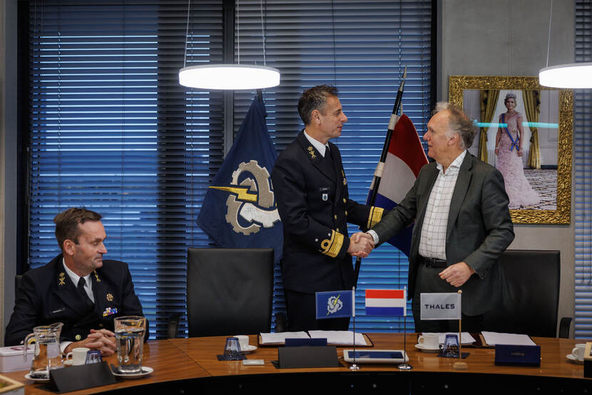 De ondertekenaars van de overeenkomst schudden elkaar de hand.