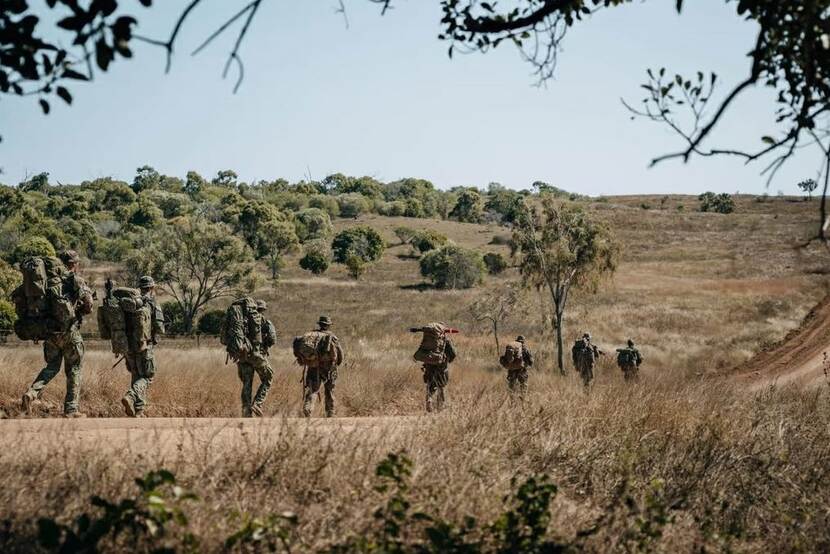 Militairen op de rug gezien lopen een weg op.