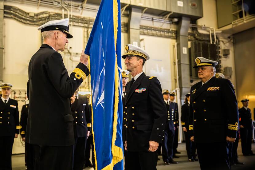 Warnaar staat naast de vlag die bij de ceremonie werd overhandigd.