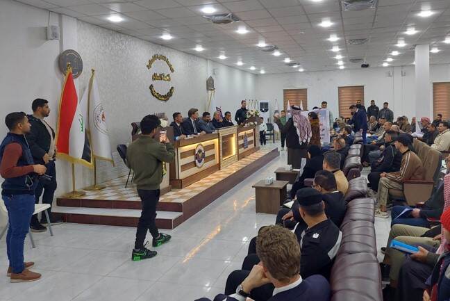 De minister spreekt een zaal toe in irak.