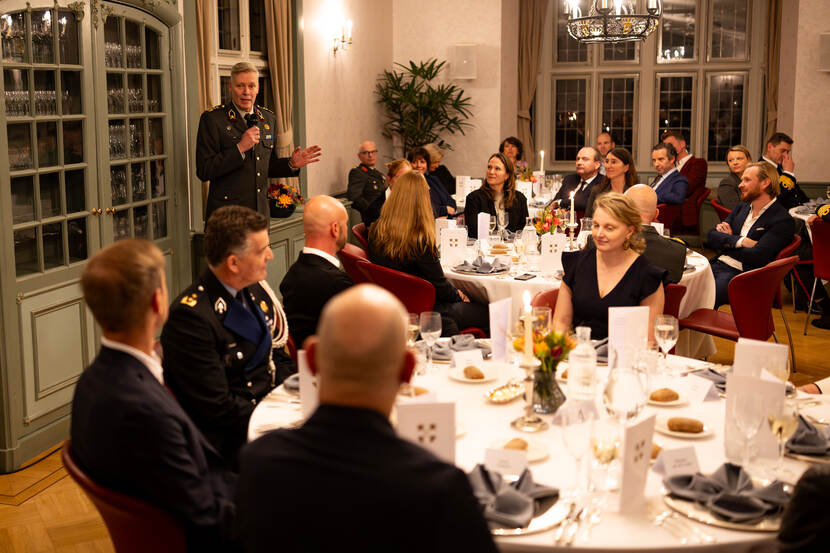 Organisator luitenant-generaal Jan-Willem Maas houdt een toespraak. Om hem heen zitten mensen aan tafels.