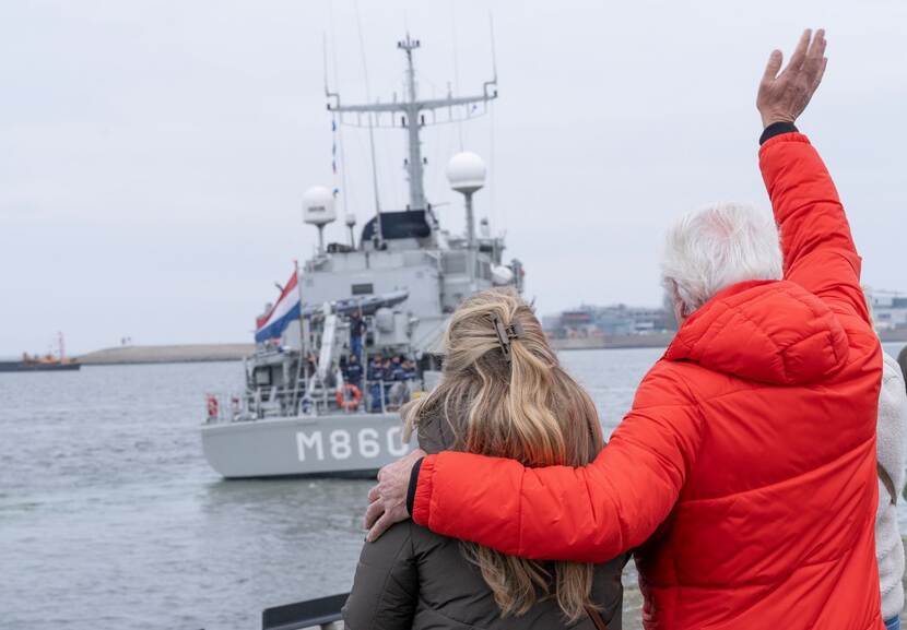 Een man en een vrouw op de kade zwaaien naar de bemanning van het schip.