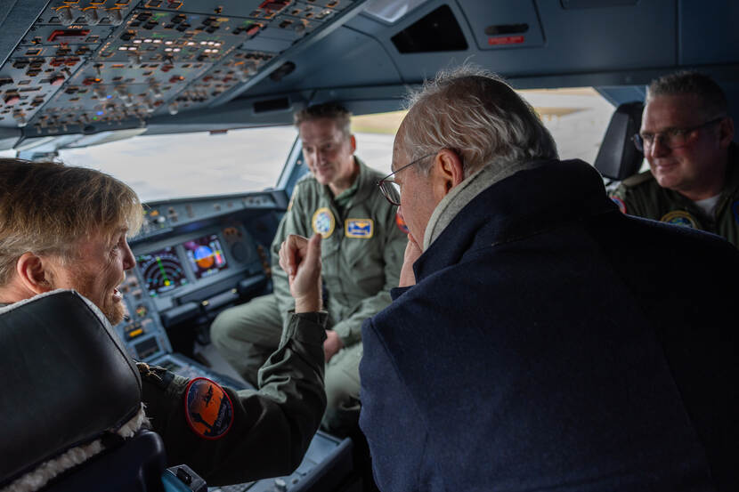 De koning en anderen in de cockpit van een vliegtuig.