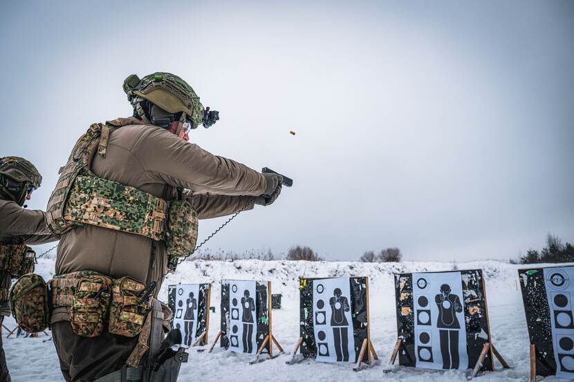 Militairen schieten op schijven in winters landschap.