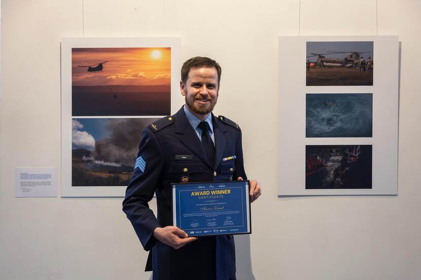 Aaron Zwaal in uniform houdt een lijst omhoog waarop in gele letters te lezen valt: AWARD WINNER.