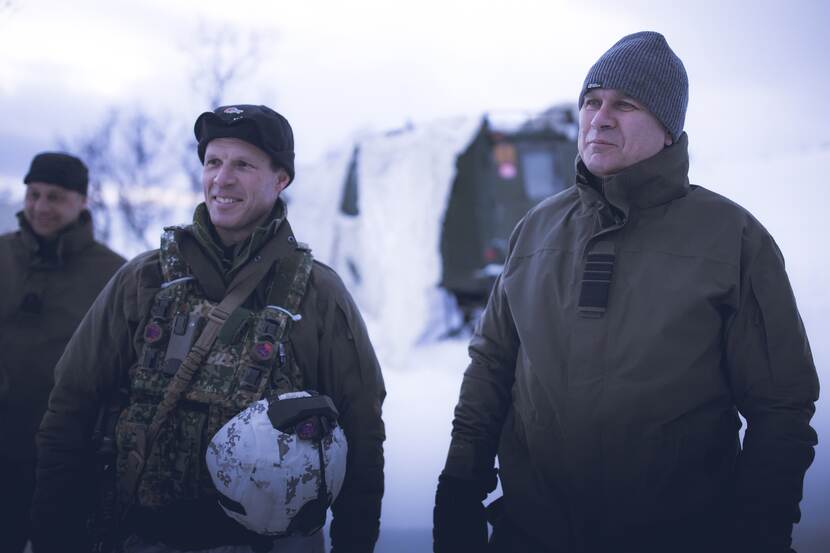 De CDS warm aangekleed met een militair naast hem, in de sneeuw.