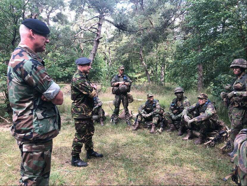 CDS praat met militairen in het bos