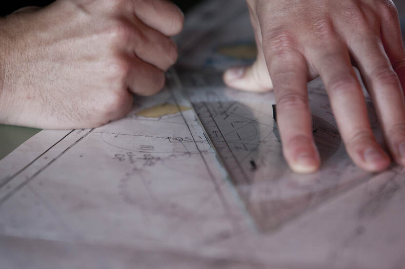 Hand drukt geodriehoek op een zeekaart.