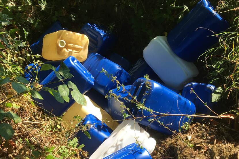 Plastic jerrycans in het gras.