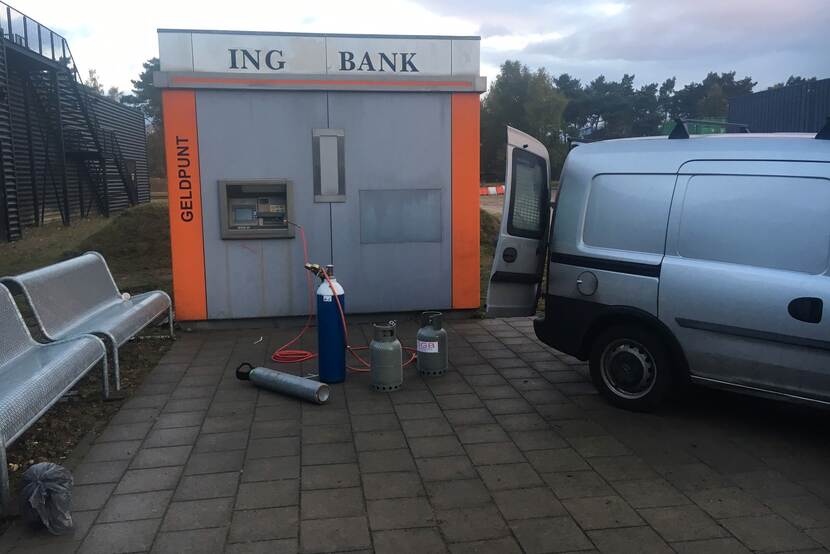 Geldpunt van een ING-bank. Voor het geldpunt staan gasflessen en een auto.