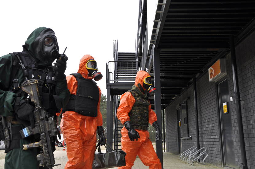 Personen in beschermende pakken naderen een PostNL agentschap.