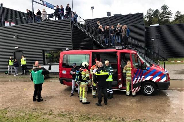 Mensen wachten buiten op metrostation. Brandweerwagen en hulpverleners aanwezig.