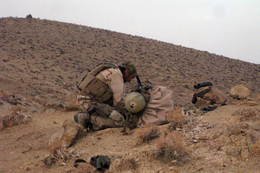 Een militair op een heuvel in Afghanistan aan het werk.