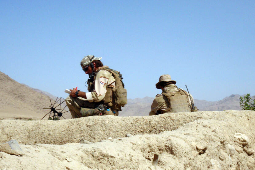 Militairen geknield op een heuvel in Afghanistan.