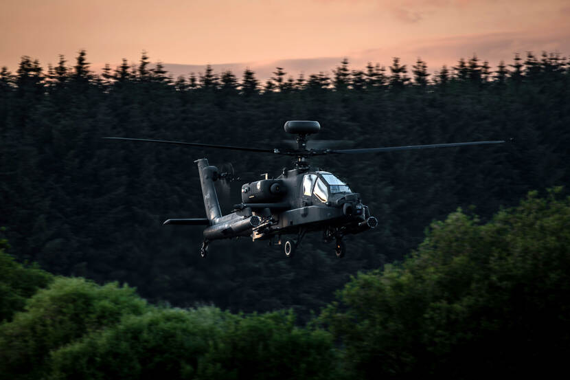 Een Apache-helikopter vliegt tijdens de avond.