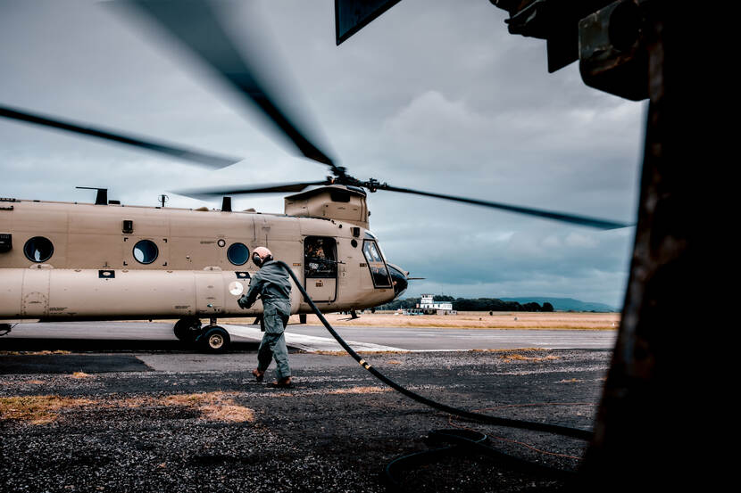 Een militair loopt naar een Chinook-helikopter om het van brandstof te voorzien.