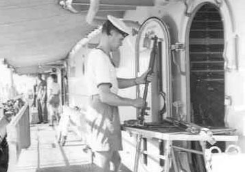 Marineman maakt geweer schoon aan boord van schip (1955).