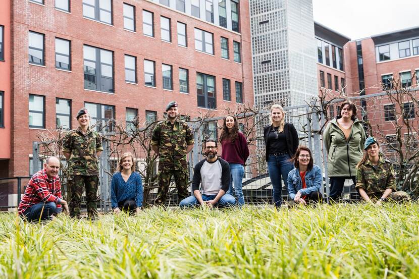 Een groep mensen poseren voor de foto met als achtergrond een gebouw.