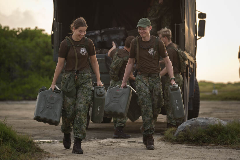 2 militairen lopen met jerrycans.