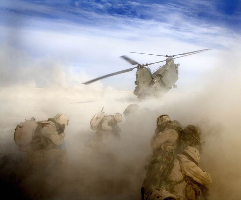 Een Chinook-helikopter stijgt op en maakt stofwolk.