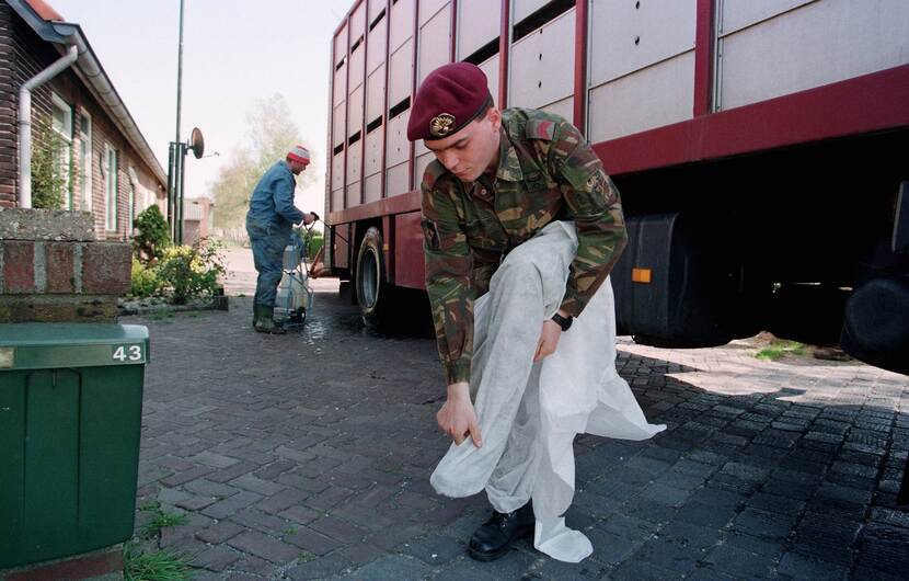 Een militair trekt beschermende kleding aan tijdens de Varkenspestcrisis (Operatie Knor) 1997.