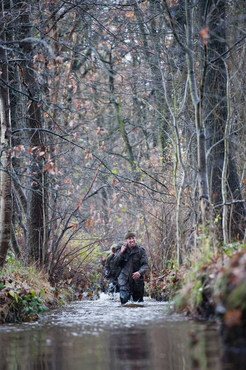 Commando's lopen door water in het bos.