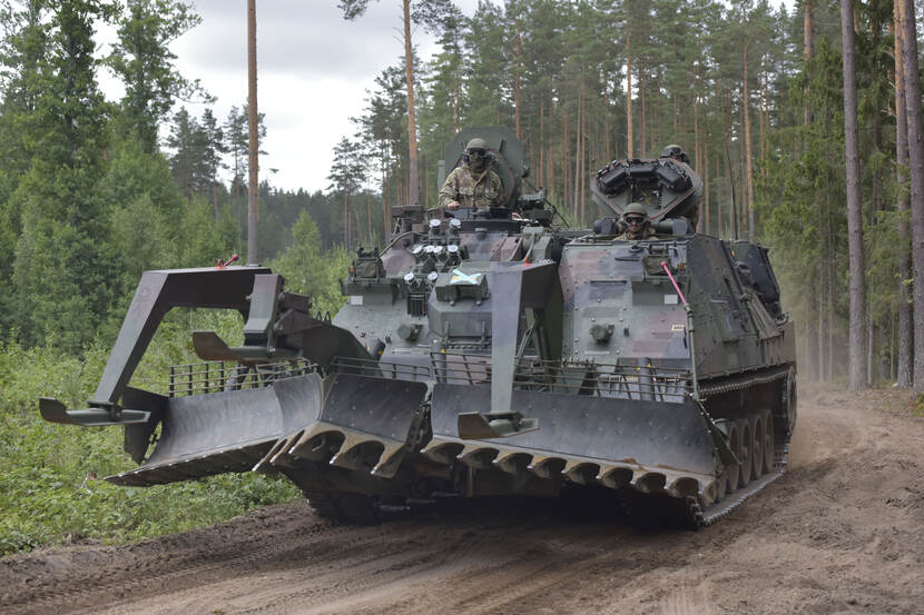 Een genietank rijdt over een zandweg in het bos.