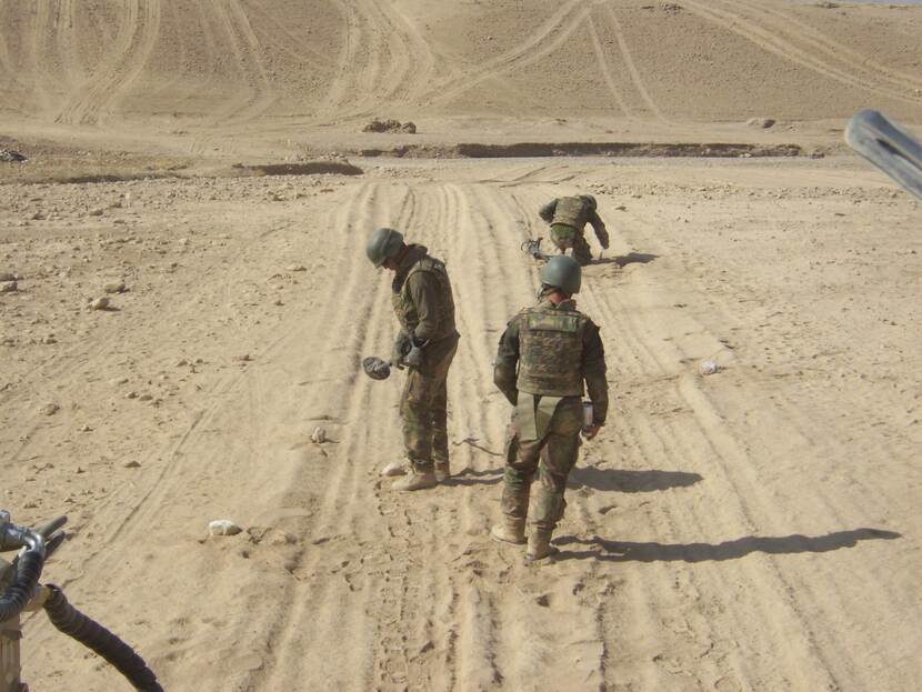 3 militairen zoeken in het Afghaanse zand naar explosieven.