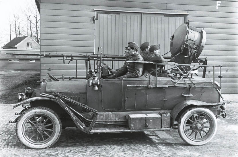 4 militairen zitten in een auto met een zoeklicht.