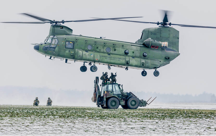 Een graaflaadcombi wordt door een Chinook-helikopter opgetild.