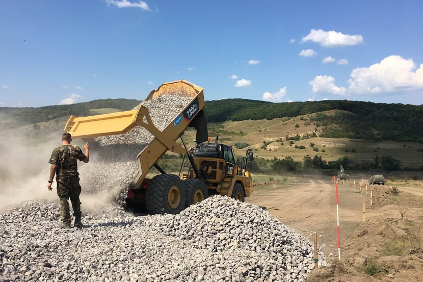 Een kiepauto lost stenen tijdens een oefening in Roemenië.