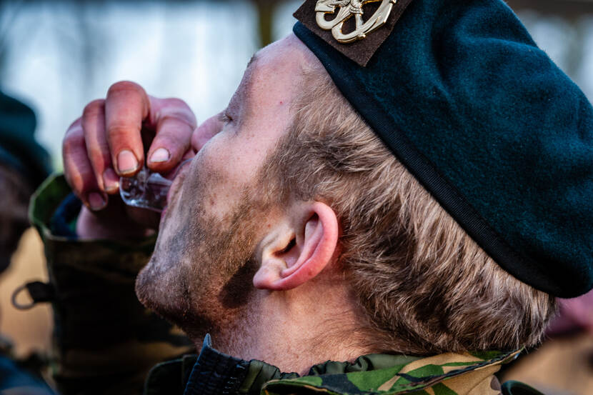 Een militair drink uit een klein glaasje.