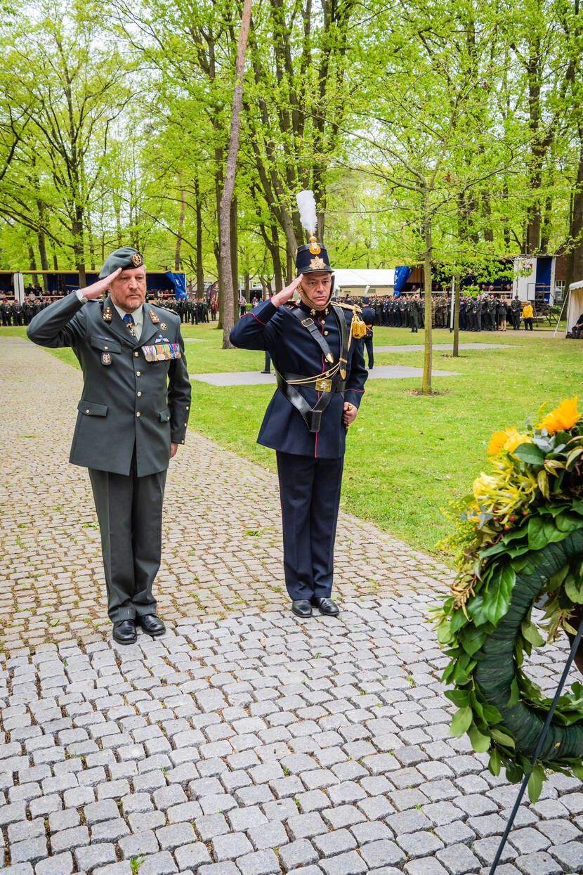 De regimentscommandant en -adjudant salueren voor een krans.