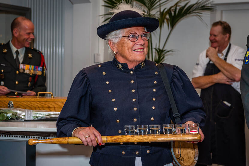 Marketenster houdt een peddel vast met daarop 6 met drank gevulde kleine glaasjes.