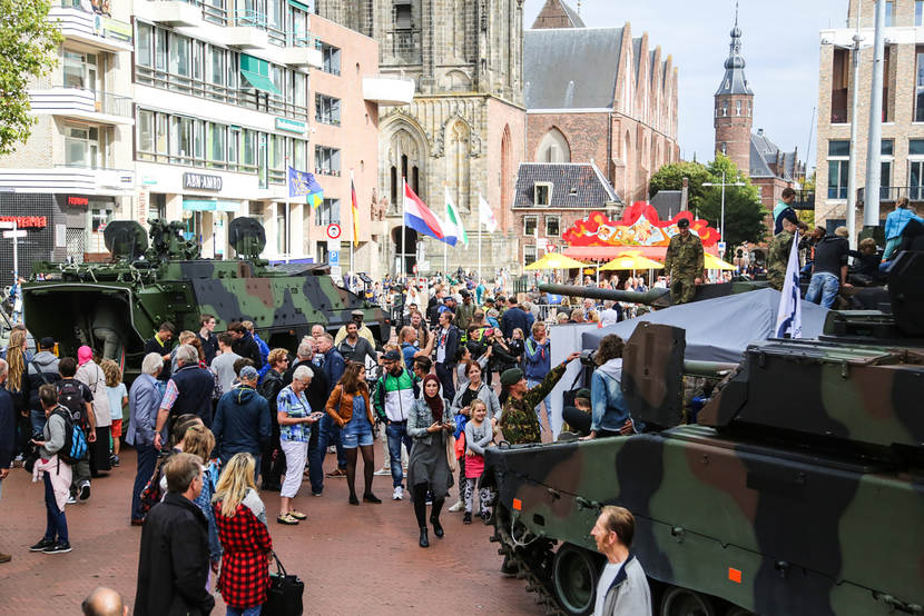 Landmachtvoertuigen tussen publiek in straten tijdens open dag.